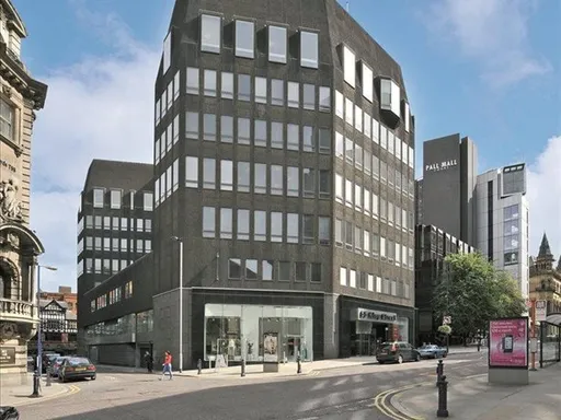 An exterior view of 55 King Street Manchester, a dark-coloured office building situated on a cross roads. 55 King Street is a client of analytics4energy and made significant saving using our Energy Performance Contract.
