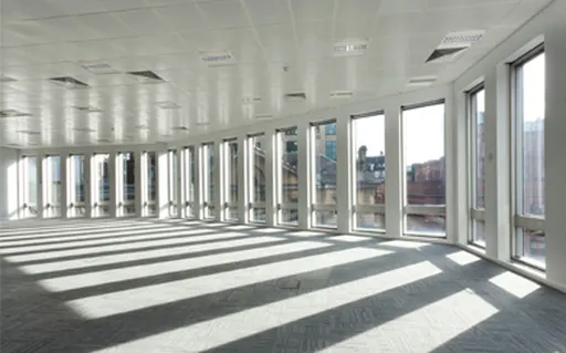 An office space with a large wall of windows and sunlight streaming through them at 55 King Street in Manchester. 55 King Street is a client of analytics4energy and made significant saving using our Energy Reduction Contract.