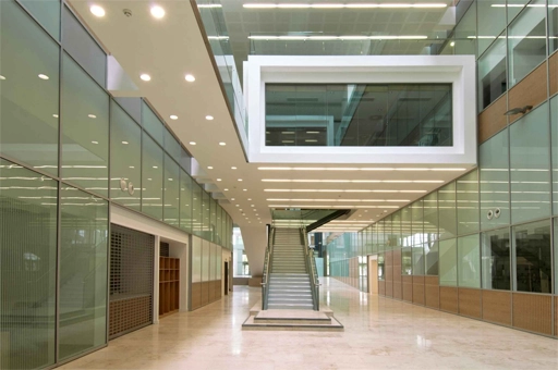 A modern corridor and staircase lined with glass panels at the Laboratory of Molecular Biology, which includes energy saving features and BMS designed by 4energy group